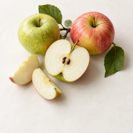 Pommes fraîches entières et tranchées vertes et rouges avec feuilles vertes sur fond clair.