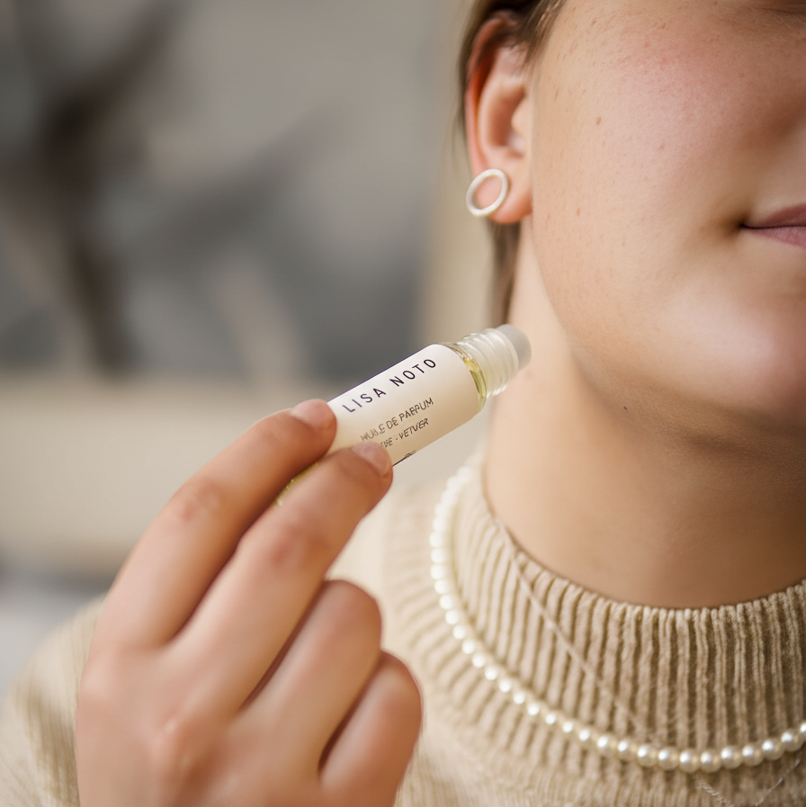 Petit flacon en verre transparent avec étiquette crème et bouchon à bille, huile de parfum rose-vétiver.