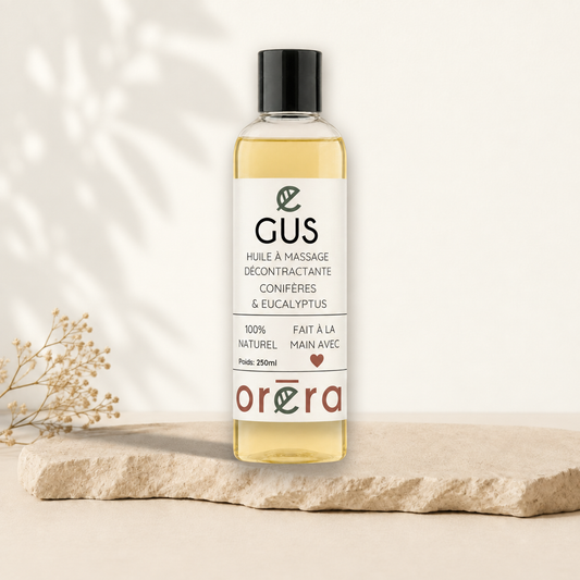 Flacon transparent d’huile à massage jaune pâle avec étiquette blanche et texte noir, bouchon noir.