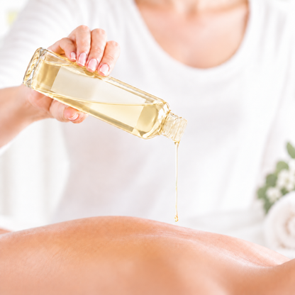 Bouteille en verre transparent versant huile jaune clair sur dos nu pour massage détente.
