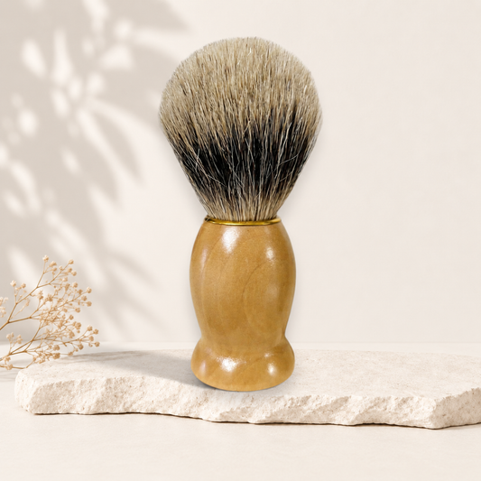 Blaireau en bois clair avec poils denses beige et noir, poignée ergonomique lisse.