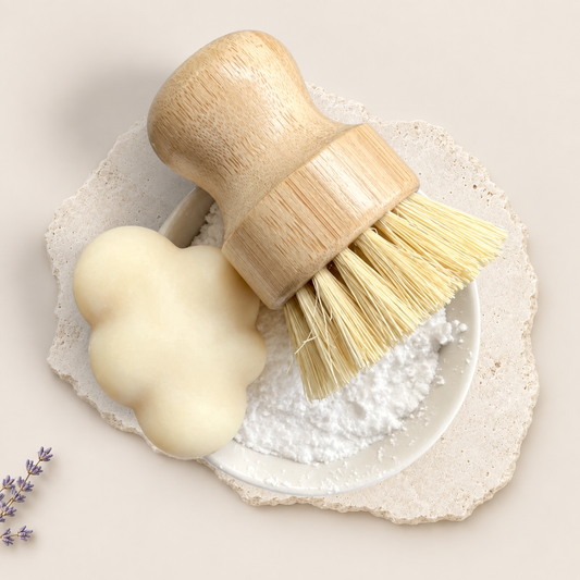 Brosse à vaisselle en bois clair avec poils naturels et pain de savon crème en forme de nuage sur assiette à rebords.