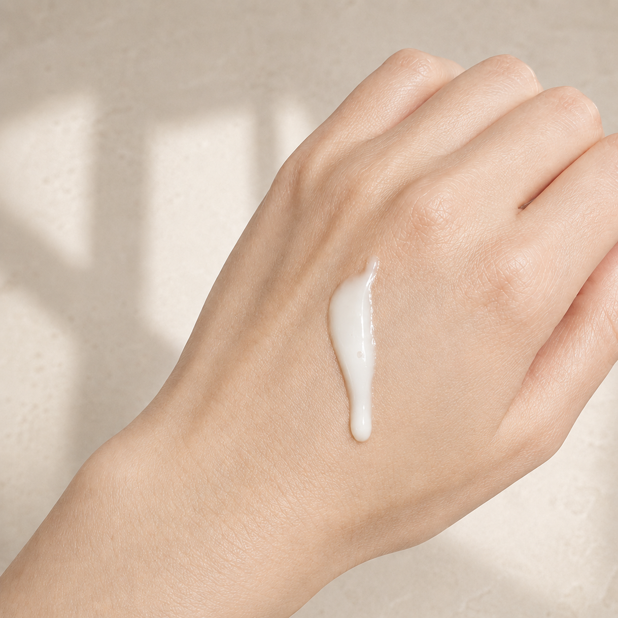 Lait nettoyant visage YLINA fleur de néroli blanc sur main, soin naturel ORÉRA éco-luxe fabriqué au Québec sans cruauté.