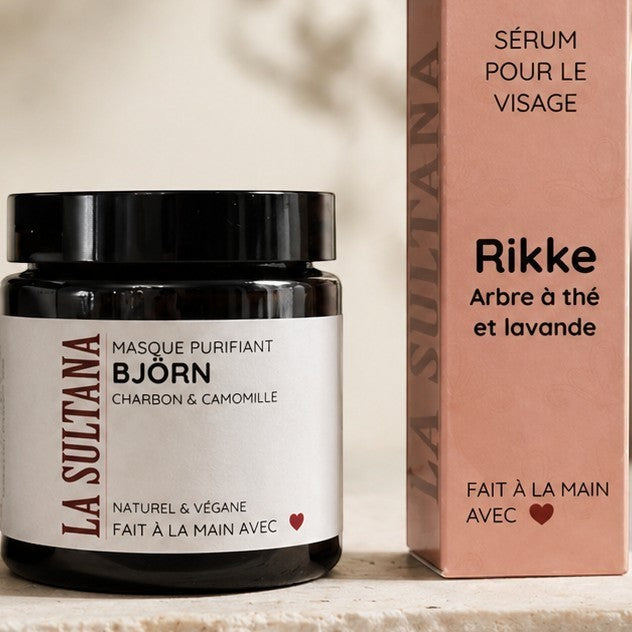 Pot noir mat avec étiquette beige et texte noir, sérum visage Rikke arbre à thé & lavande, boîte beige assortie.