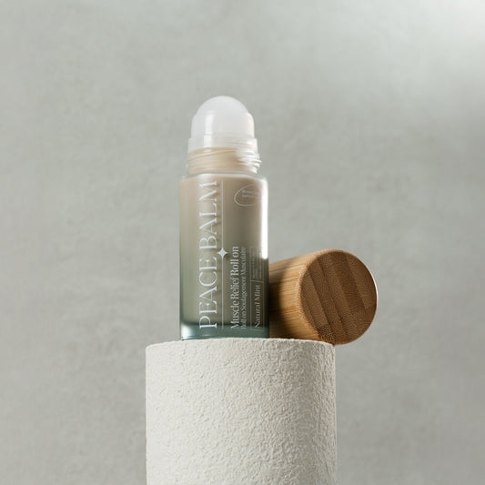 Baume solide mint naturel ORÉRA avec bouchon en bois posé sur cylindre blanc texturé.