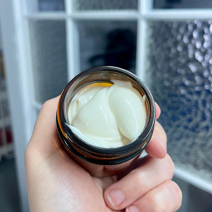 Pot en verre ambré contenant une crème hydratante blanche, soins naturels ORÉRA, produit artisanal québécois sans cruauté.