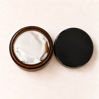 Pot en verre ambré avec crème blanche onctueuse et bouchon noir mat ouvert.