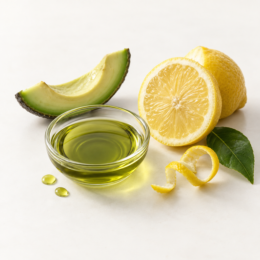 Tranche d'avocat, huile verte dans bol transparent, citron jaune tranché et pelure en spirale.