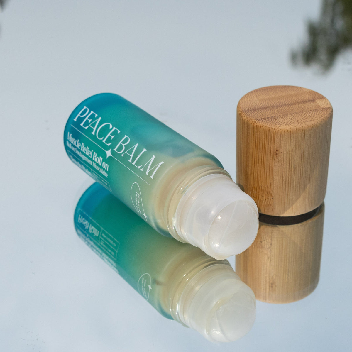 Stick baume transparent avec étiquette turquoise et bouchon en bois clair, finition lisse.