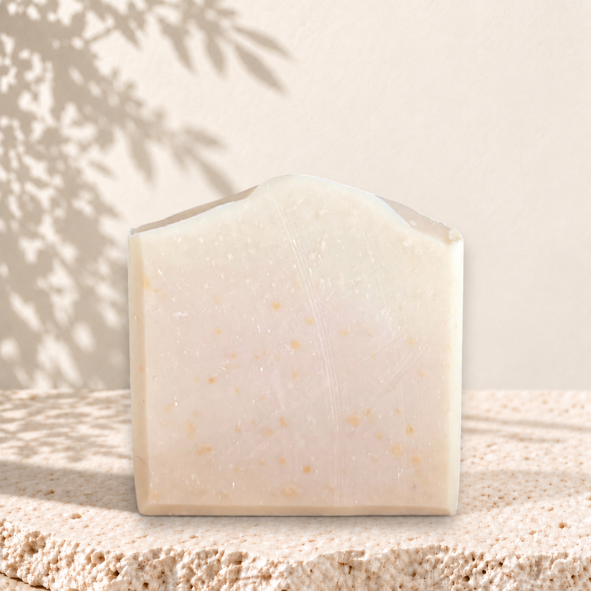 Savon rectangulaire crème avec grains d’avoine visibles, texture douce et naturelle.