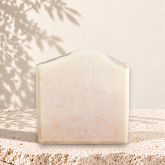 Savon rectangulaire crème avec grains d’avoine visibles, texture douce et naturelle.
