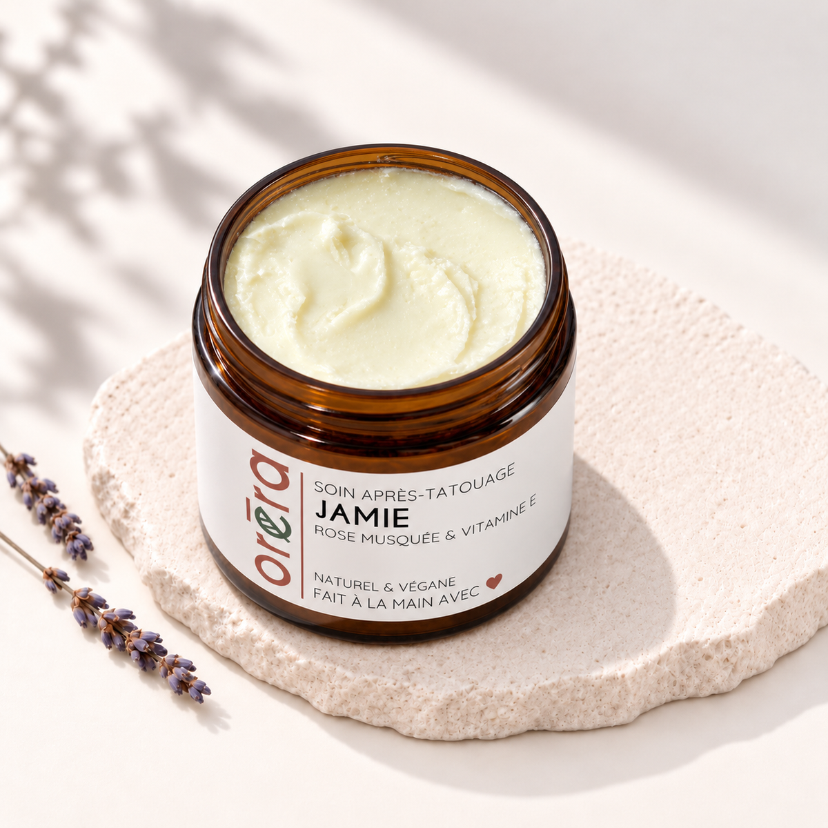 Pot ambré ouvert de soin après-tatouage JAMIE, rempli de baume jaune pâle.