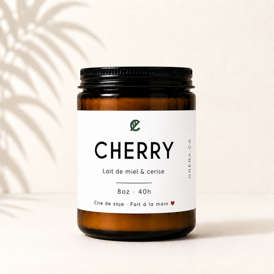 Bougie artisanale en verre ambré avec étiquette blanche, parfum cerise et lait de miel, cire de soya.