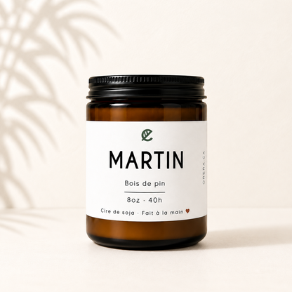 Bougie en pot verre ambré avec étiquette blanche, parfum bois de pin, couvercle noir.