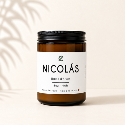 Bougie en verre ambré avec étiquette blanche NICOLÁS baies d'hiver, couvercle noir.