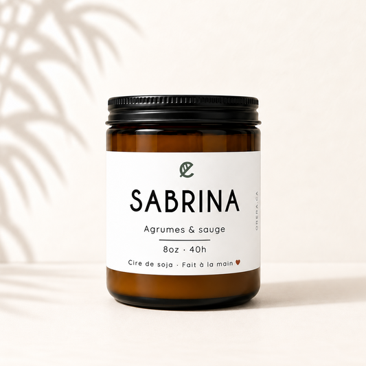 Bougie de soya dans pot verre ambré avec étiquette blanche et bouchon noir, parfum agrumes et sauge.