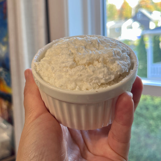 Bol en céramique blanc rempli d’un cake vaisselle mousseux tenu à la main.