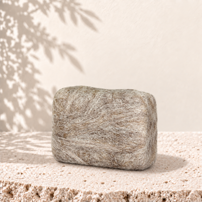 Savon rectangulaire beige enveloppé de laine feutrée d'alpaga, texture douce et naturelle.