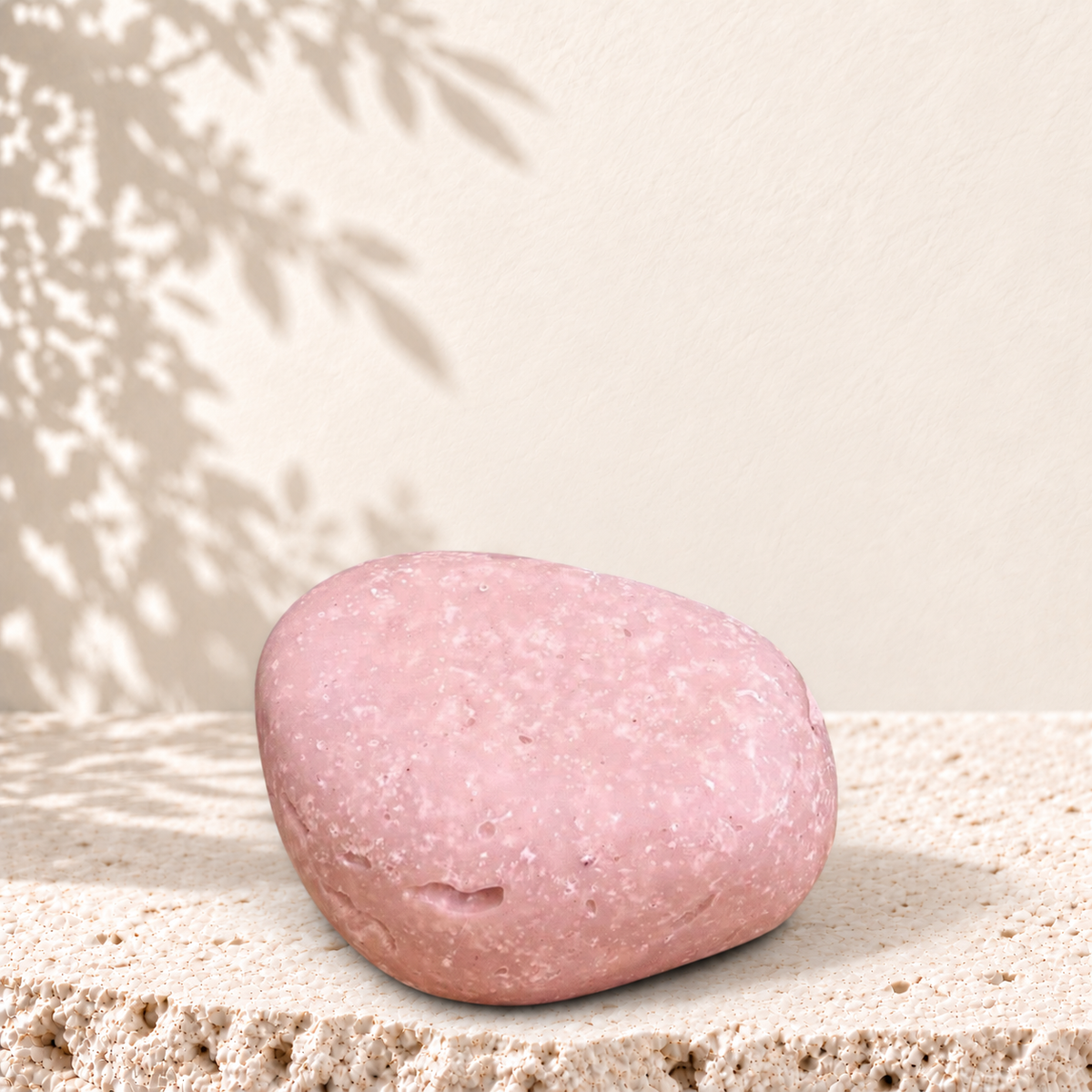 Savon exfoliant rose pâle avec particules de sel d'Himalaya, forme ovale lisse.
