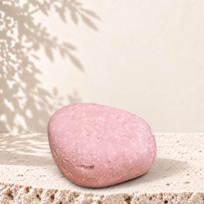 Savon exfoliant rose pâle avec particules de sel d'Himalaya, forme ovale lisse.