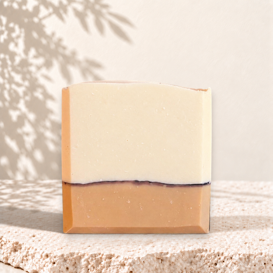 Savon rectangulaire orange et crème à deux couches avec fine ligne noire, aspect naturel et artisanal.