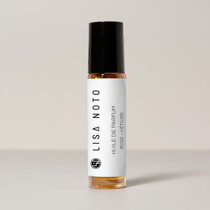 Petit flacon en verre transparent avec bouchon noir et étiquette blanche, parfum Rose-Vetiver.
