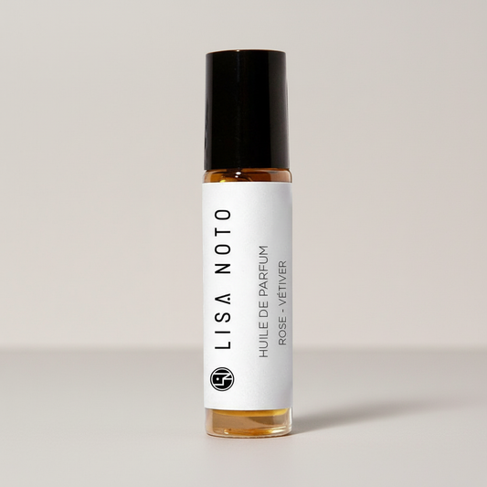 Petit flacon en verre transparent avec bouchon noir et étiquette blanche, parfum Rose-Vetiver.