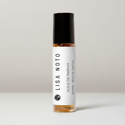 Flacon roll-on huile de parfum ambrée 10ml, étiquette blanche minimaliste, bouchon noir mat.