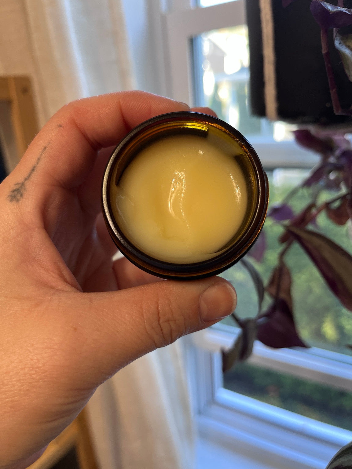 Pot ouvert de baume pour tatouage JAMIE imparfait, montrant sa texture plus liquide et fondante.