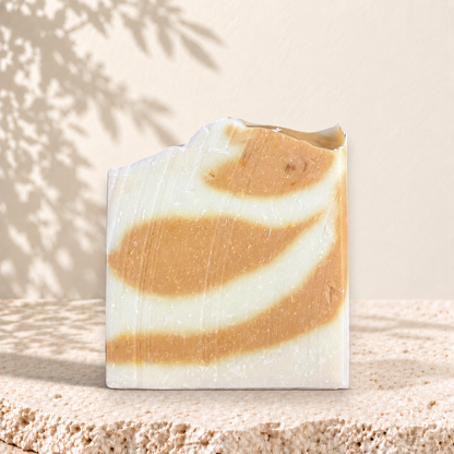 Savon artisanal carré avec marbrures blanc crème et orange doux, aspect naturel.