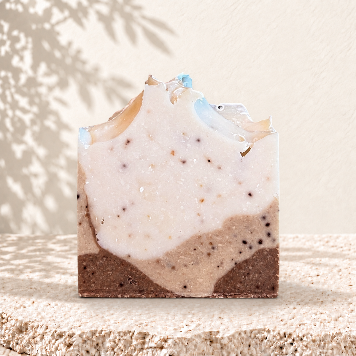 Savon carré exfoliant bicolore beige et marron avec grains de café visibles.
