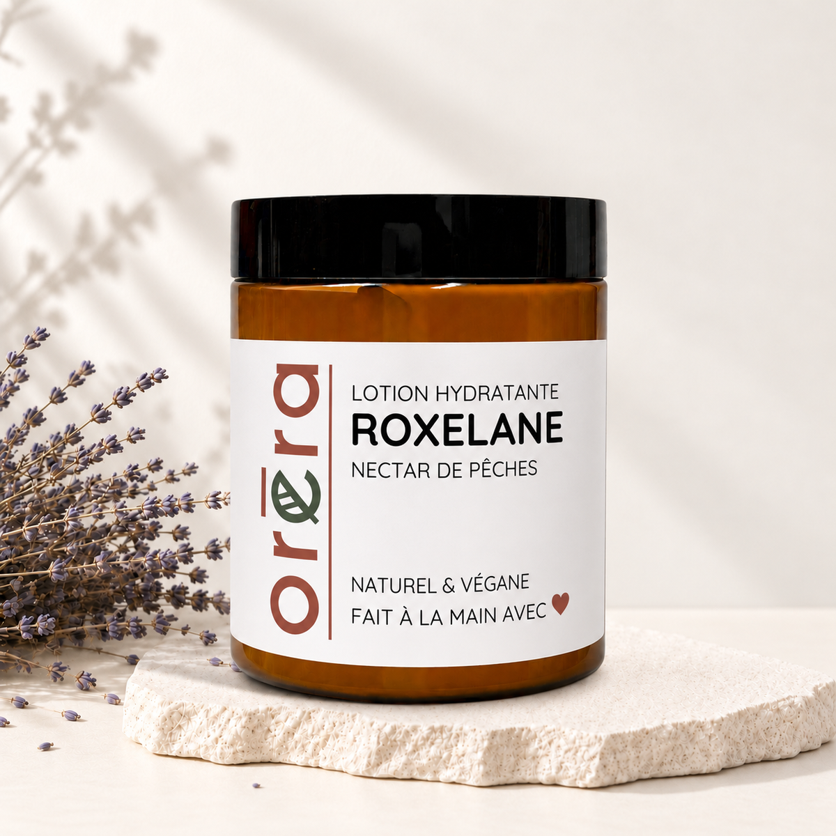 Pot ambre en verre avec couvercle noir, étiquette blanche, lotion hydratante ROXELANE nectar de pêches, style éco-luxe.