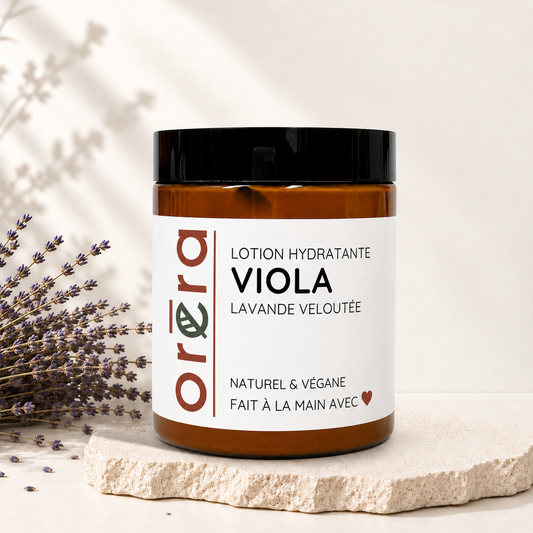 Pot ambré de lotion hydratante Viola avec étiquette blanche et couvercle noir, ambiance naturelle avec lavande.