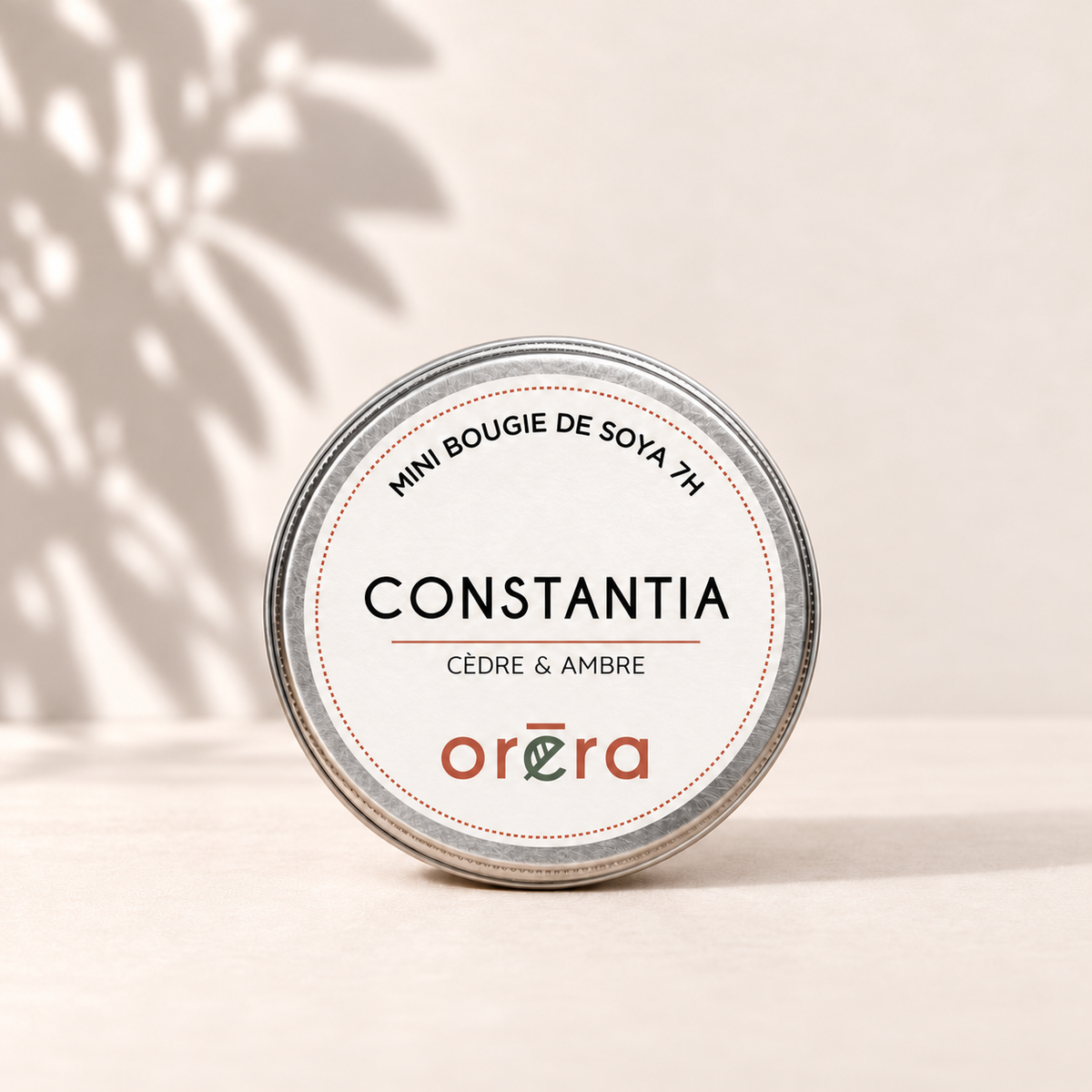 Mini bougie CONSTANTIA cèdre et ambre dans son pot métallique argenté sur fond ivoire