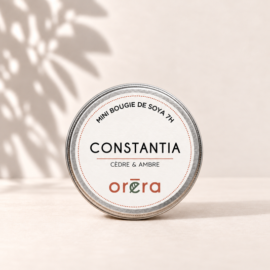 Mini bougie CONSTANTIA cèdre et ambre dans son pot métallique argenté sur fond ivoire