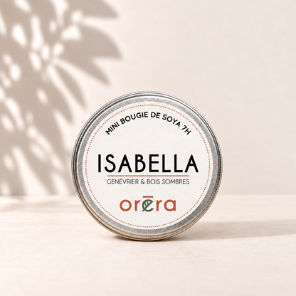 Mini bougie ISABELLA genévrier et bois sombres dans son pot métallique argenté sur fond ivoire