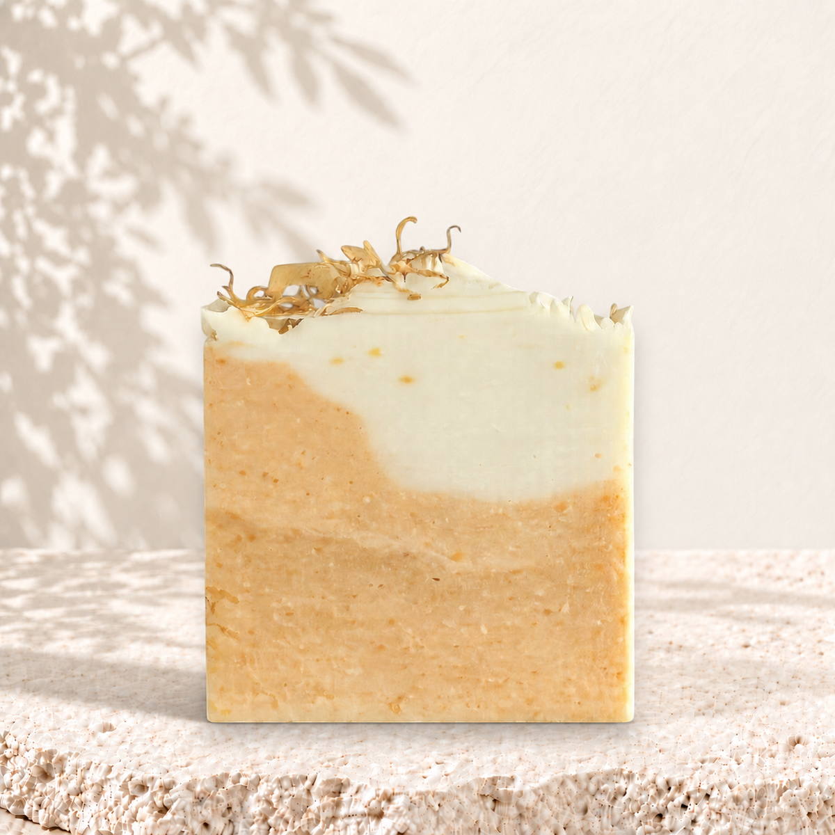 Savon carré bicolore beige et blanc avec éclats de curcuma et fleurs séchées sur le dessus.
