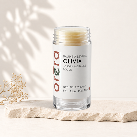 Baume à lèvres géant Oréra Olivia jaune pâle, pot cylindrique transparent avec étiquette blanche minimaliste.