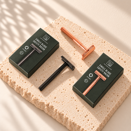 Rasoirs noir et rose doré Zero Waste MVMT avec leurs boîtes marquées, posés sur une pierre claire.