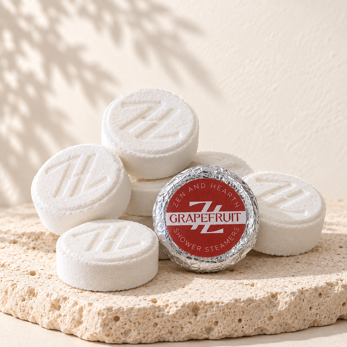 Pastilles de douche pamplemousse Zen and Hearth et leur emballage rouge, posés sur une pierre claire.