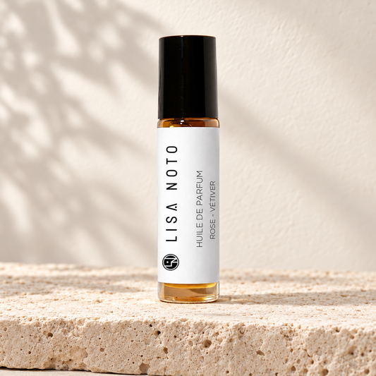 Huile de parfum Lisa Noto rose et vétiver, flacon posé sur une pierre claire.
