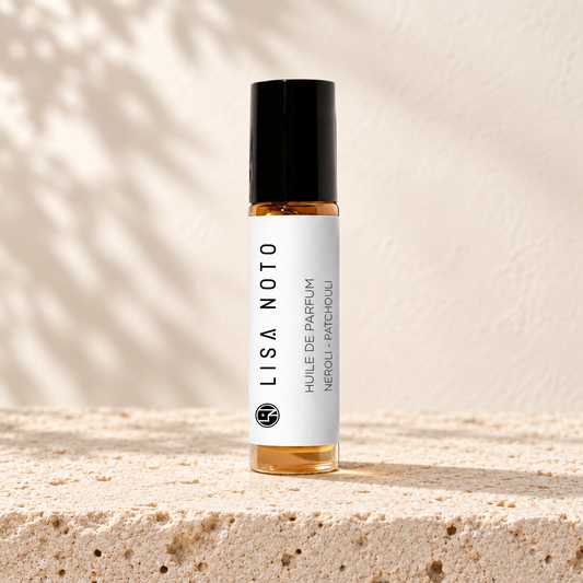 Huile de parfum Lisa Noto néroli et patchouli, flacon posé sur une pierre claire.