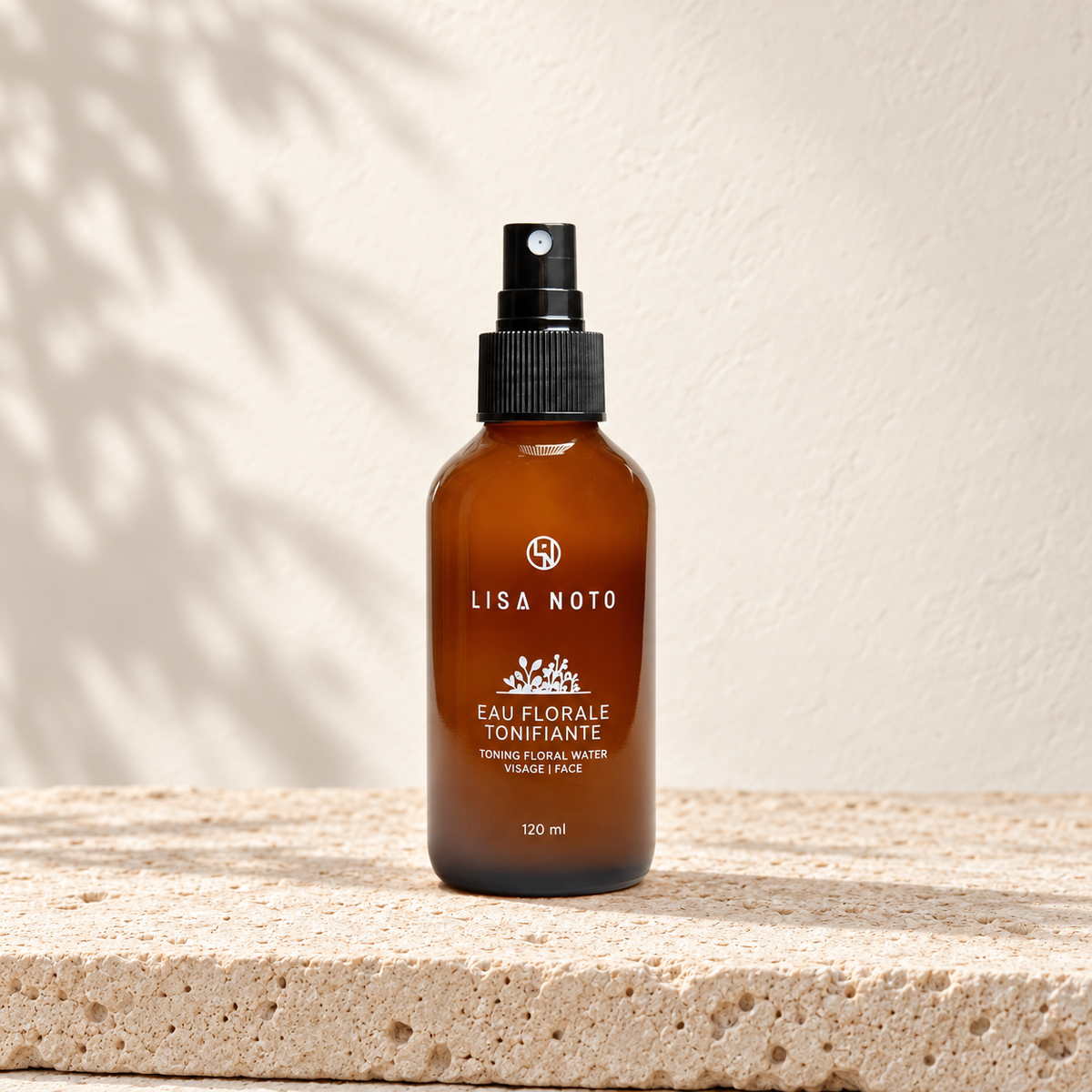 Eau florale tonifiante Lisa Noto, flacon ambré posé sur une pierre claire.
