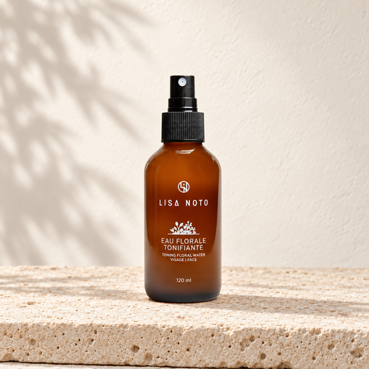 Eau florale tonifiante Lisa Noto, flacon ambré posé sur une pierre claire.