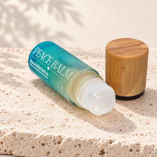 Peace Balm Fresh Rain, flacon roll-on ouvert couché avec bouchon en bois, posé sur du travertin clair.
