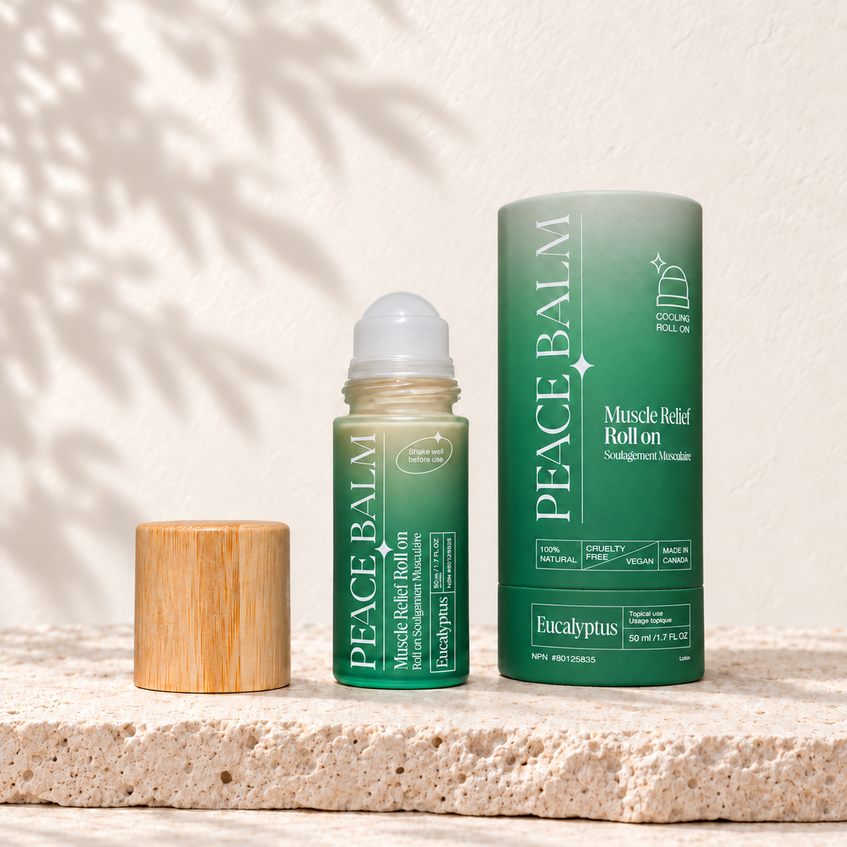 Peace Balm Eucalyptus, flacon roll-on et étui vert d’origine, posés sur du travertin clair.