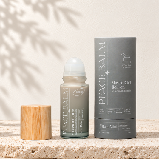 Peace Balm Natural Mint, flacon roll-on et étui gris d’origine, posés sur du travertin clair.