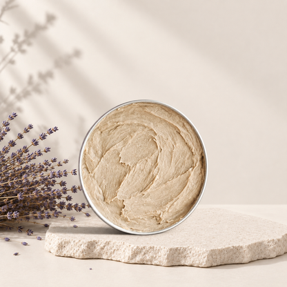 Dentifrice naturel beige en pot rond en métal posé sur pierre avec brin de lavande sèche.