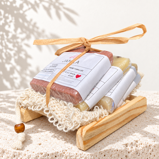 Ensemble Mignonne de quatre mini savons emballés, avec pochette en sisal, porte-savon en bois et ruban de raphia, sur fond ivoire lumineux.