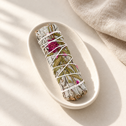 Bâton de sauge blanche et fleur de dahlia, non allumé, dans une coupelle en céramique ivoire avec du lin beige.